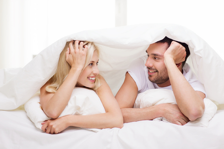 54255642-people-family-bedtime-and-happiness-concept-happy-couple-lying-in-bed-covered-with-blanket-over-head